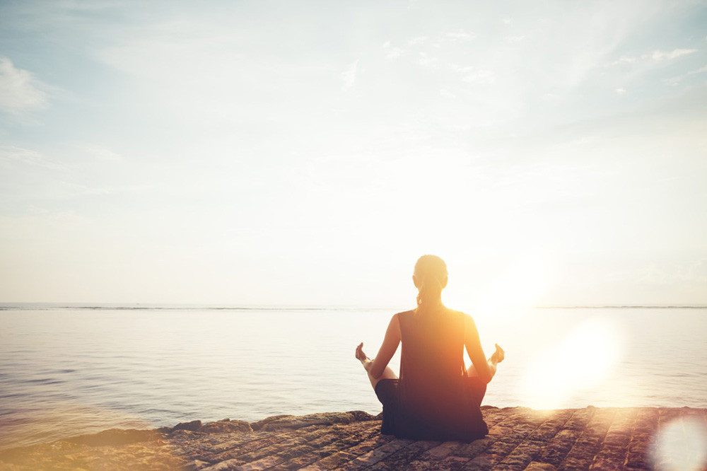 woman meditating by water